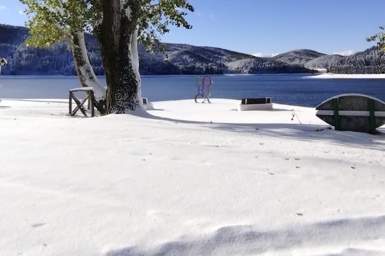Vista invernale di Lorica con la scultura colorata del borgo affacciata sul Lago Arvo innevato